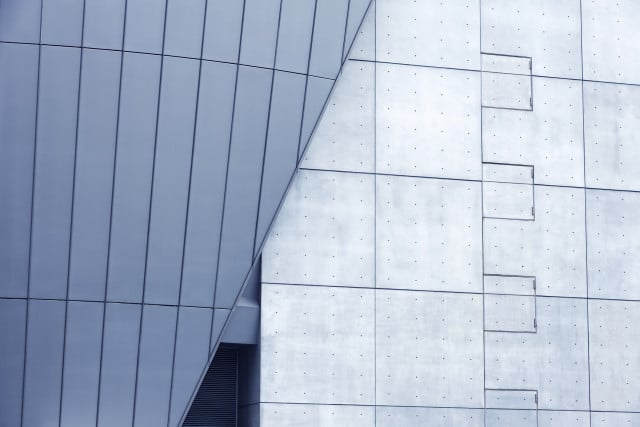 Modern building with large blue frosted glass windows aligned to a concrete wall.